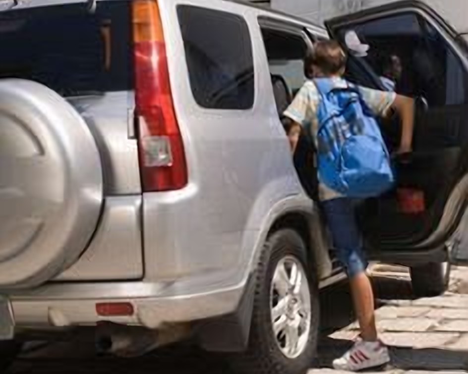 Un estudiante con mochila azul subiendo al carro para ir a la escuela